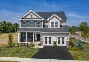 Aerial view of a two-story suburban house with a landscaped yard and clear blue skies.
